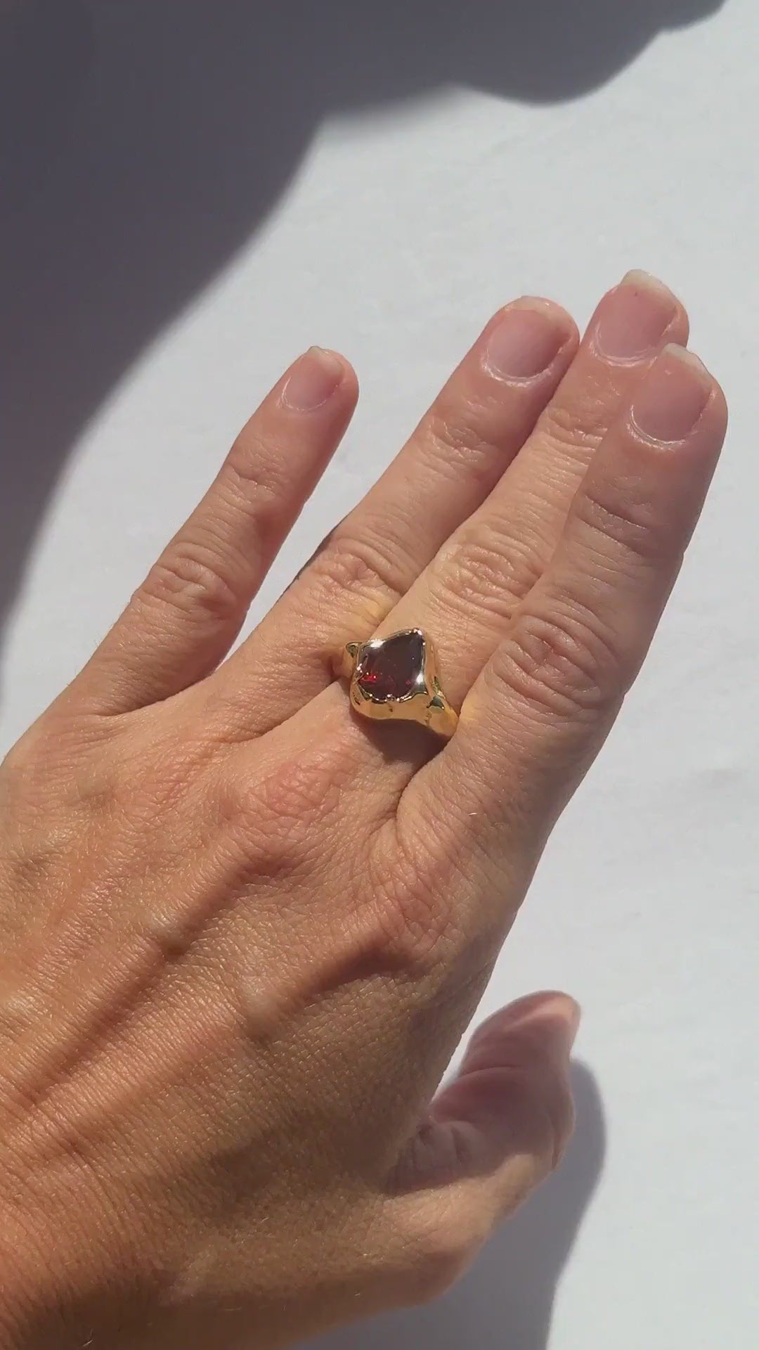 Garnet Tear Ring in rhodolite garnet worn on the hand in sunlight